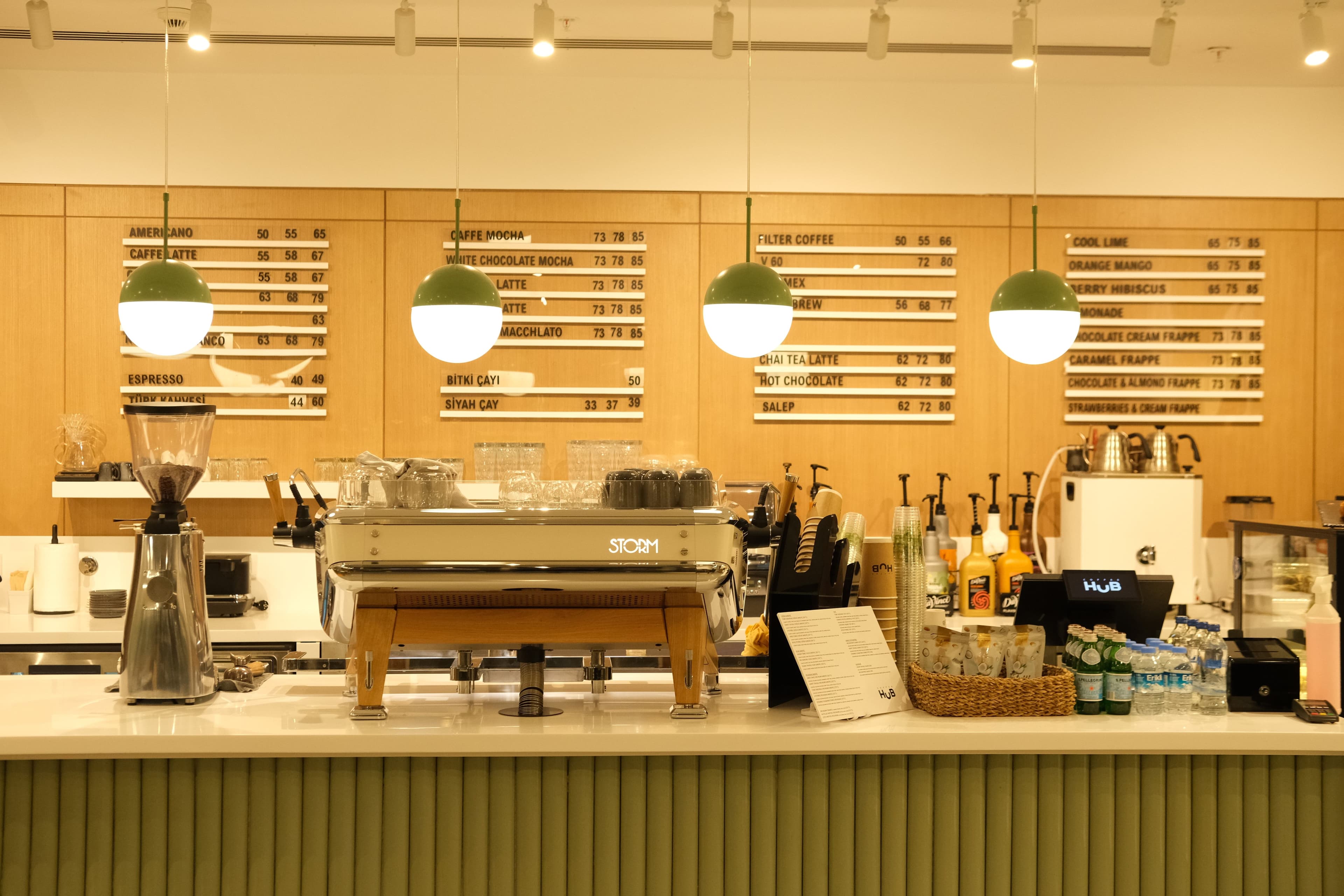Barra de cafetería iluminada con lámparas colgantes y máquina de espresso